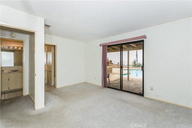 3899 28th St, Highland, CA 92346 - unfurnished bedroom featuring access to exterior, carpet floors, baseboards, ensuite bathroom, and a textured ceiling