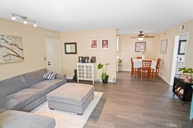 living area with a ceiling fan, a textured ceiling, visible vents, and wood finished floors
