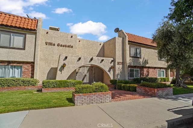 31732 Ridge Route Rd Unit 111, Castaic, CA 91384 - view of front of house featuring stucco siding, brick siding, a front yard, and a tiled roof