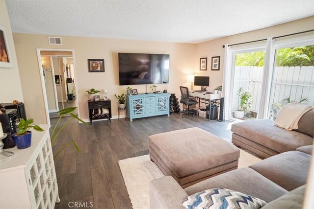 living room with a textured ceiling, hardwood / wood-style floors, and visible vents