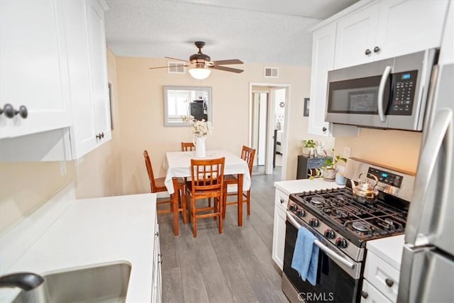31732 Ridge Route Rd Unit 111, Castaic, CA 91384 - kitchen with stainless steel appliances, white cabinetry, light wood-style floors, a ceiling fan, and light countertops