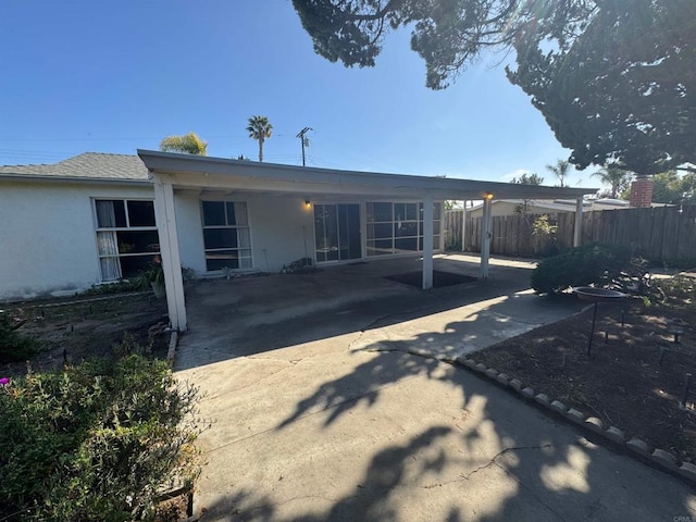 rear view of property with fence, stucco siding, and a patio area