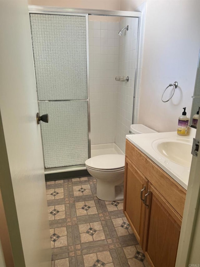 bathroom with vanity, a stall shower, and toilet