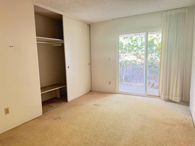 unfurnished bedroom featuring a closet, carpet flooring, a textured ceiling, and access to exterior