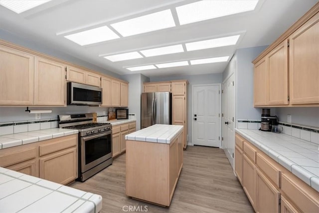 317 Alder St, Arroyo Grande, CA 93420 - kitchen featuring light brown cabinets, stainless steel appliances, tile countertops, light wood-type flooring, and a kitchen island