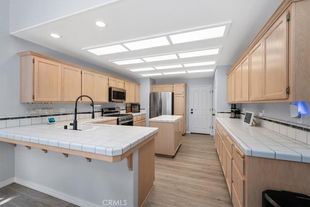 317 Alder St, Arroyo Grande, CA 93420 - kitchen featuring a sink, light wood-style floors, light brown cabinets, stainless steel appliances, and a peninsula