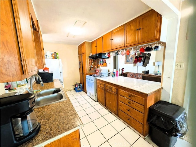 14136 Osage Rd, Apple Valley, CA 92307 - kitchen with light tile patterned floors, a sink, brown cabinetry, white appliances, and under cabinet range hood