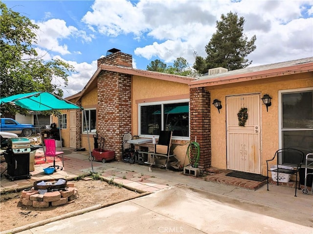 14136 Osage Rd, Apple Valley, CA 92307 - back of property featuring a patio, stucco siding, a fire pit, and a chimney