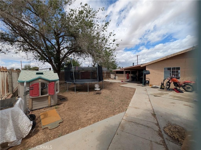 14136 Osage Rd, Apple Valley, CA 92307 - view of yard with an outdoor structure, a storage shed, a trampoline, a patio area, and a fenced backyard