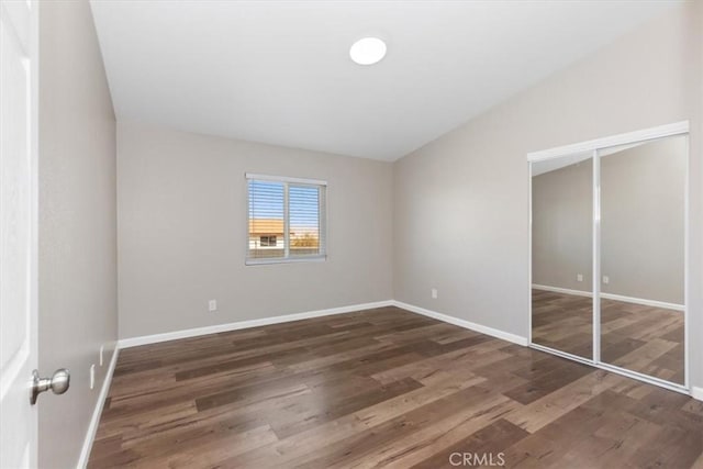 unfurnished bedroom with baseboards, wood finished floors, and a closet