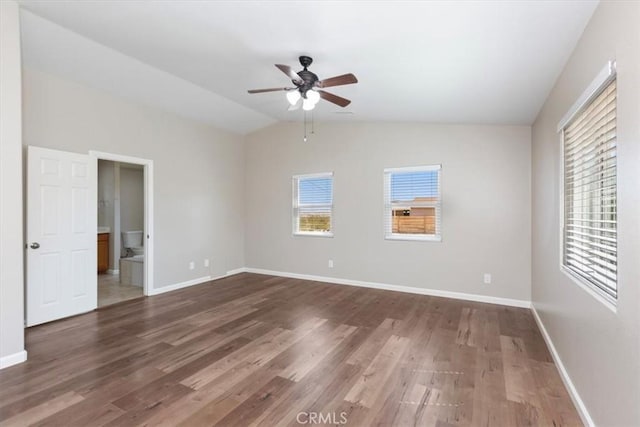unfurnished bedroom with wood finished floors, lofted ceiling, baseboards, connected bathroom, and a ceiling fan