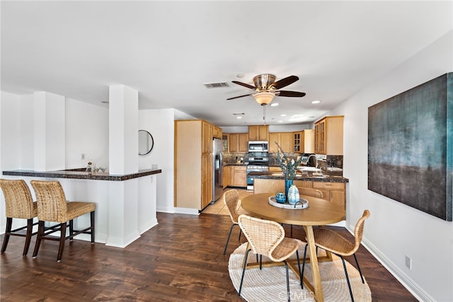 dining room with visible vents, a ceiling fan, baseboards, and wood finished floors