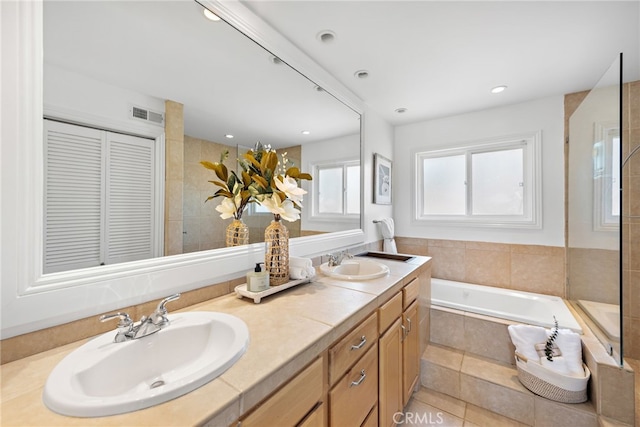 bathroom with double vanity, visible vents, a sink, and a bath
