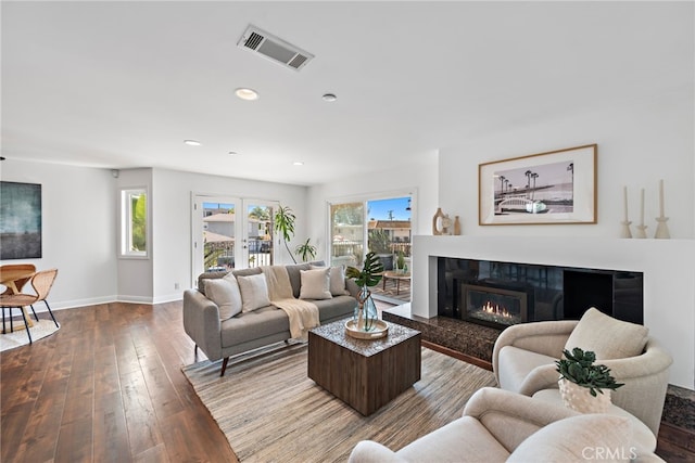 living area with a fireplace, recessed lighting, baseboards, visible vents, and hardwood / wood-style flooring