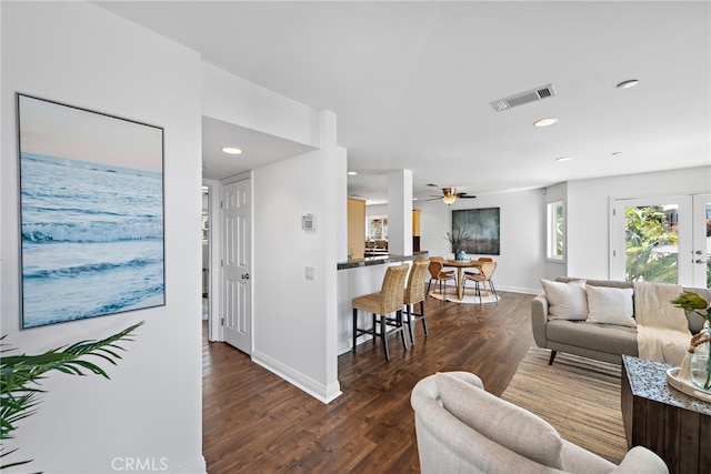living area with baseboards, visible vents, and wood finished floors