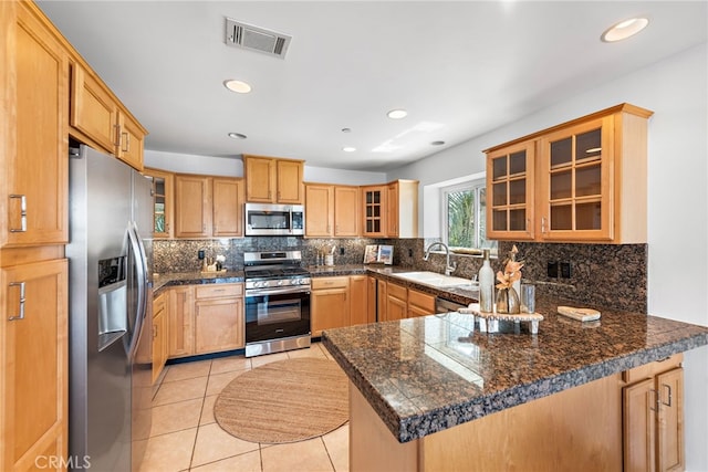 kitchen featuring decorative backsplash, visible vents, a sink, a peninsula, and stainless steel appliances