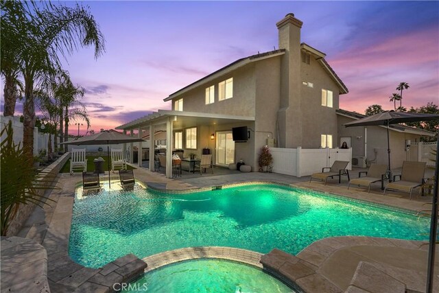 view of pool featuring a patio area, fence, and a pool with connected hot tub