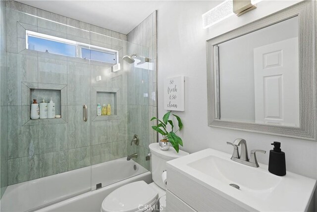 full bathroom featuring vanity, combined bath / shower with glass door, and toilet