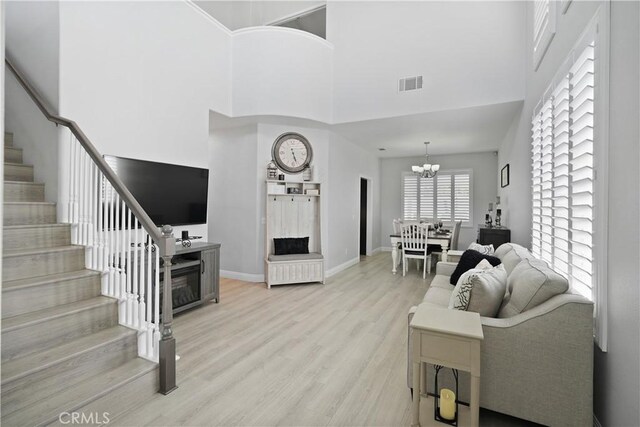 living room featuring stairs, visible vents, a towering ceiling, and a fireplace