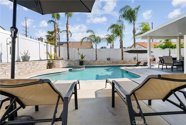view of pool featuring a fenced backyard, a pool with connected hot tub, and a patio area