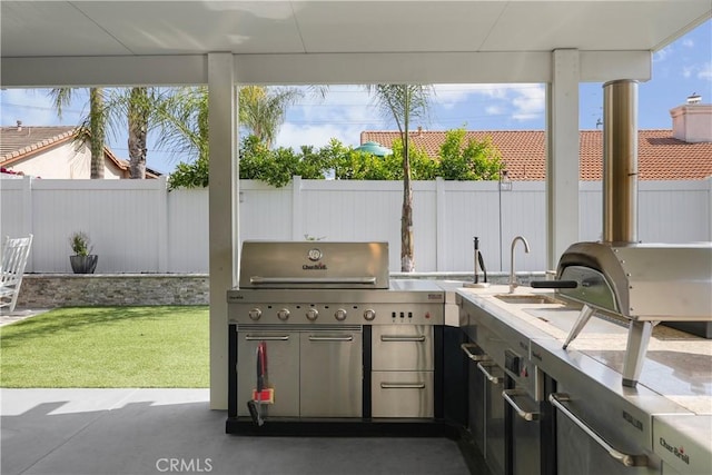 view of patio / terrace with exterior kitchen, a fenced backyard, and a grill