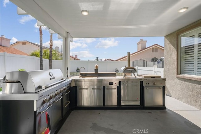 view of patio with a fenced backyard, grilling area, and exterior kitchen