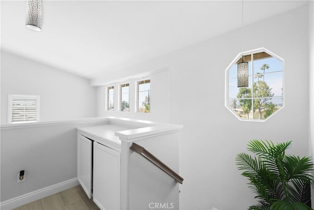 laundry area with light wood-type flooring and baseboards