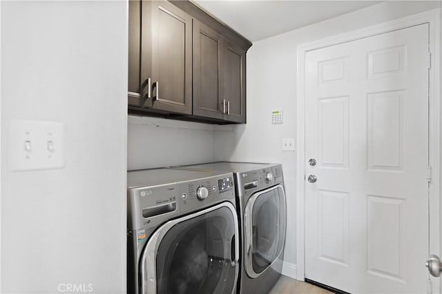 clothes washing area with cabinet space, baseboards, and washer and dryer