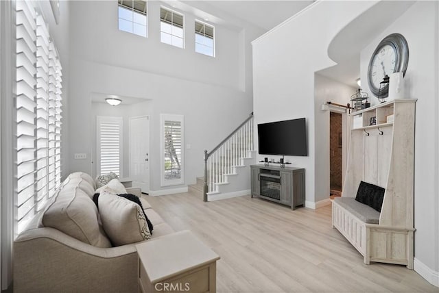 living room featuring baseboards, a barn door, light wood-style flooring, and a high ceiling