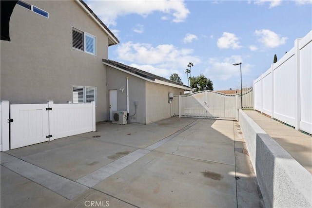 view of side of home featuring fence, ac unit, stucco siding, a gate, and a patio