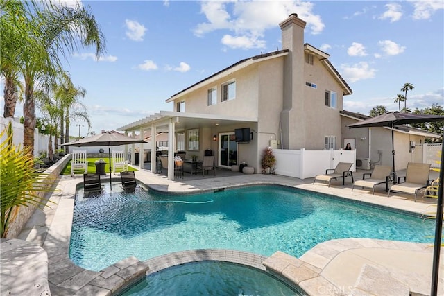 view of pool with a patio area, fence, and a pool with connected hot tub