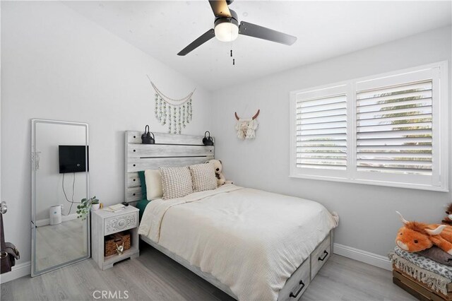 bedroom featuring baseboards, light wood-style flooring, and ceiling fan