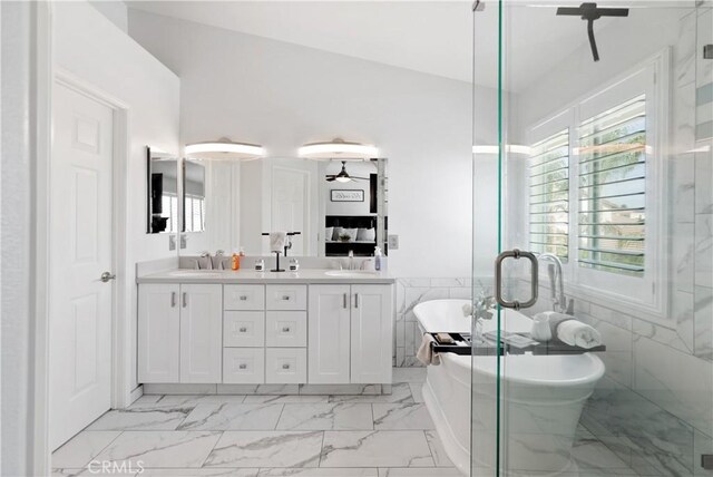 bathroom with double vanity, a freestanding bath, a sink, and marble finish floor