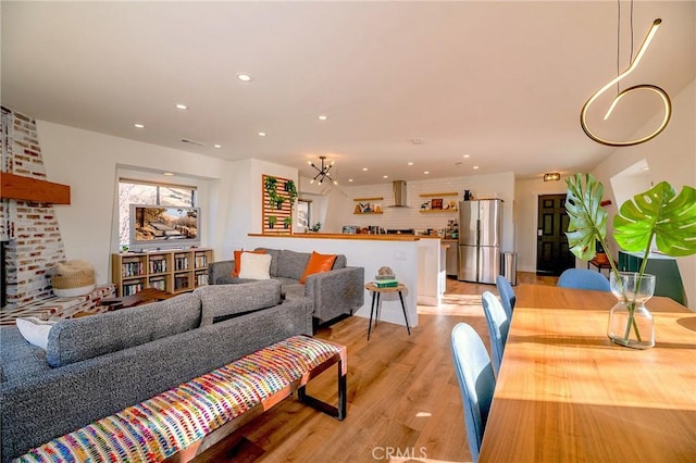 living area featuring recessed lighting, light wood-style flooring, and a notable chandelier