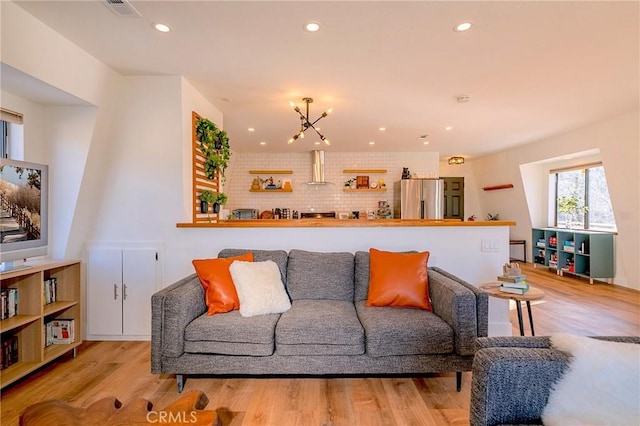 living area with recessed lighting, a notable chandelier, light wood-type flooring, and visible vents
