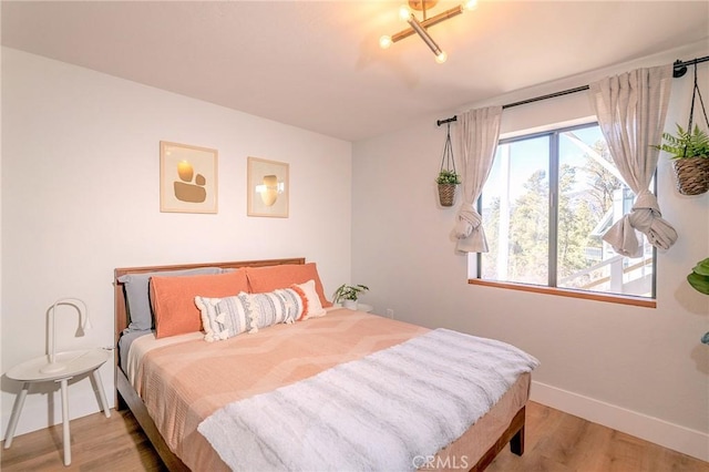 bedroom featuring baseboards, multiple windows, and wood finished floors