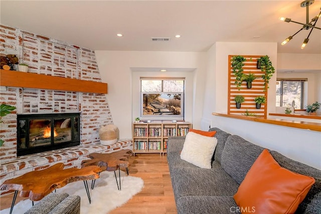 living area featuring recessed lighting, wood finished floors, visible vents, and a fireplace
