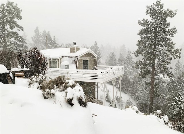 snow covered property with a chimney