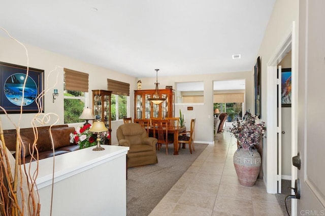 living room with light tile patterned floors, baseboards, and light carpet