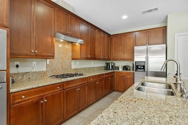 kitchen with visible vents, under cabinet range hood, a sink, appliances with stainless steel finishes, and light tile patterned floors
