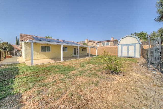 24731 Huntley Dr, Moreno Valley, CA 92557 - rear view of property featuring a storage unit, a fenced backyard, roof mounted solar panels, an outbuilding, and a patio