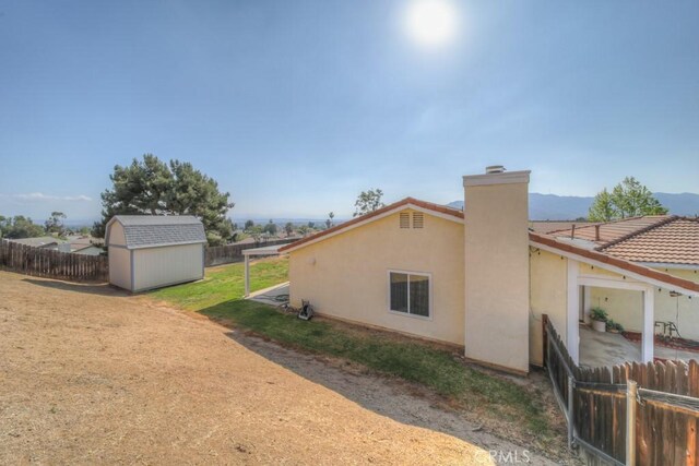 24731 Huntley Dr, Moreno Valley, CA 92557 - view of home's exterior featuring a fenced backyard, stucco siding, a storage shed, and a chimney