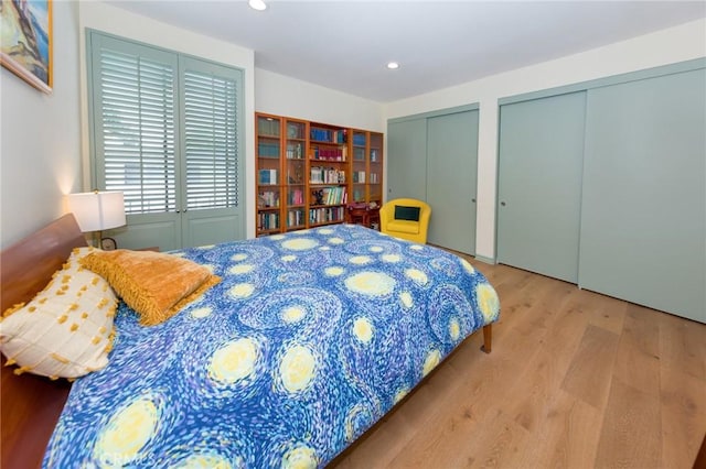 bedroom featuring recessed lighting, multiple closets, and wood finished floors