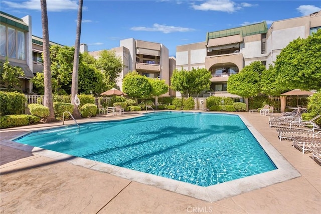 community pool with fence and a patio area