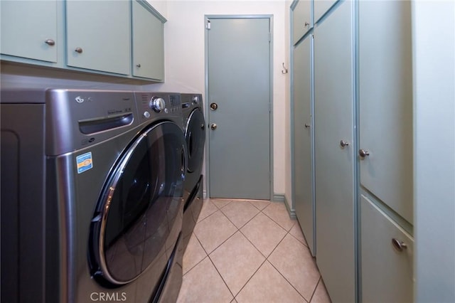 clothes washing area featuring cabinet space, light tile patterned floors, and washer and clothes dryer