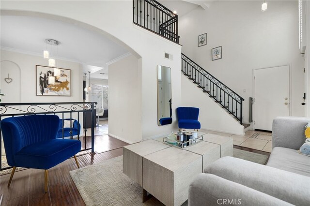 living room featuring visible vents, arched walkways, stairway, baseboards, and ornamental molding