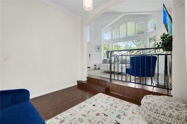 bedroom with crown molding, wood finished floors, baseboards, arched walkways, and vaulted ceiling