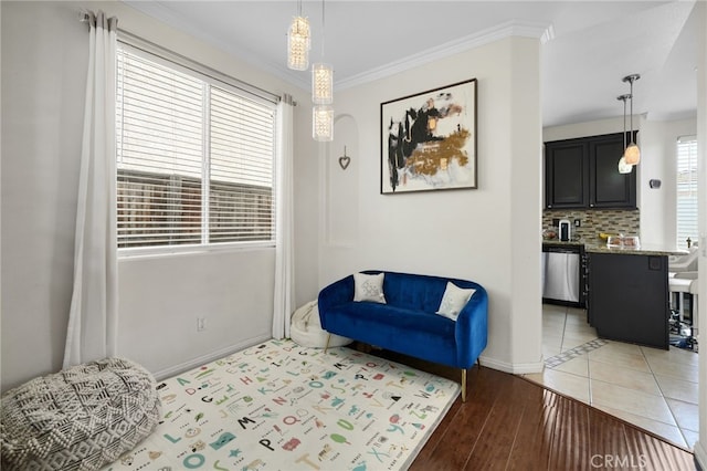 living area featuring baseboards, ornamental molding, and light wood-type flooring