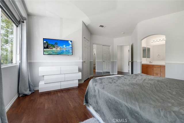 bedroom featuring visible vents, baseboards, wood finished floors, and multiple windows