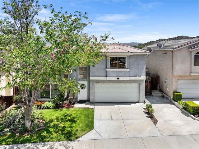 view of front of house featuring concrete driveway, a tiled roof, an attached garage, and stucco siding